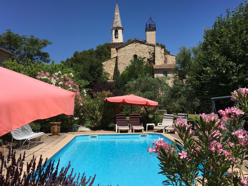 a swimming pool in front of a building with a church at Domaine Lafayette in Loriol-du-Comtat
