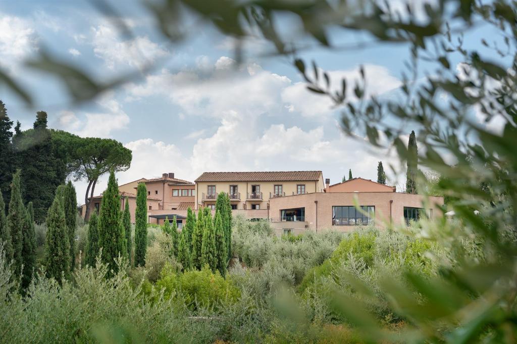 a building in the middle of a field with trees at Villasanpaolo Resort & Spa in San Gimignano