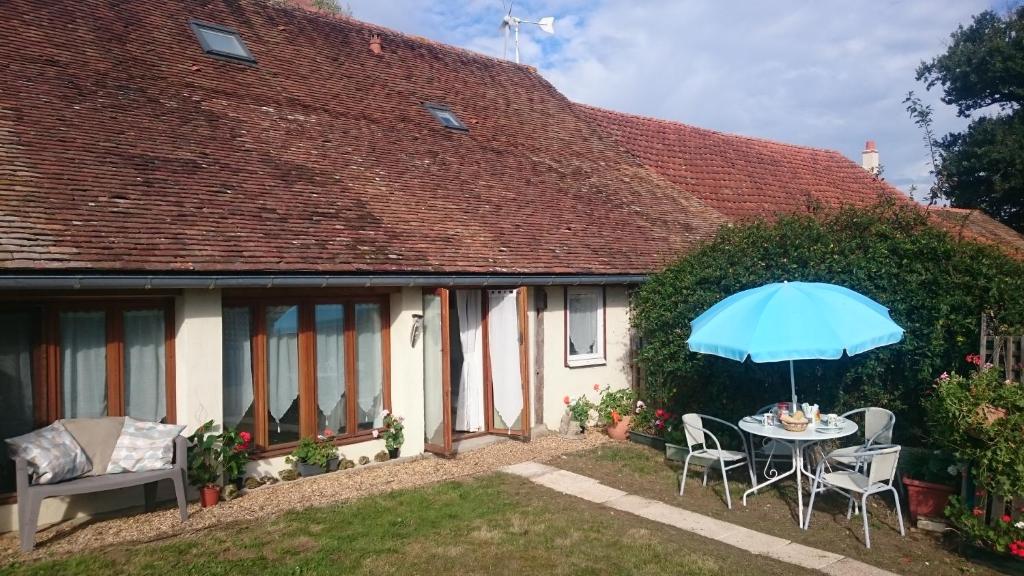 a house with a table and a blue umbrella at Le Poirier Perfect for 2 adults and 2 children Heated Pool and Games Room in Auverse
