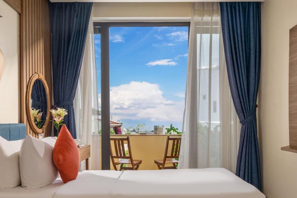 a bedroom with a bed and a window with a view at NA Hoian Hotel in Hoi An
