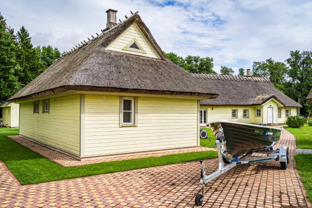 a large yellow house with a thatched roof at Uuelu turismitalu in Kõrkküla