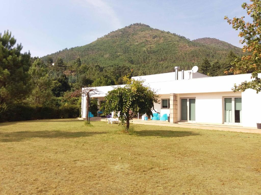 a white house with a mountain in the background at Casa da Fonte Trigueira in Mondim de Basto