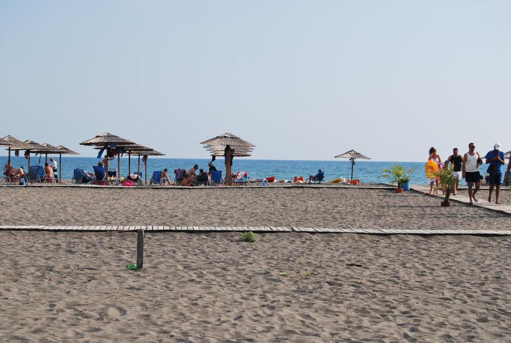 a group of people on a beach with umbrellas at H and H Guesthouse in Velipojë