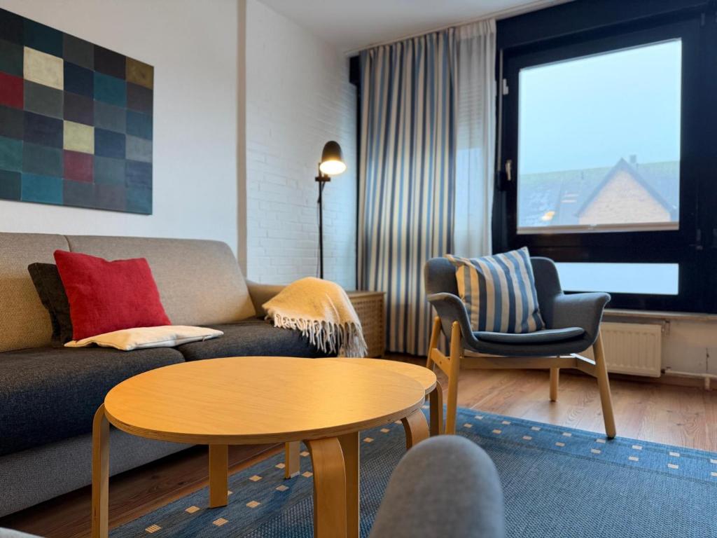a living room with a couch and a table and chairs at Gemütliches App in Westerland mit Hund in Süderende