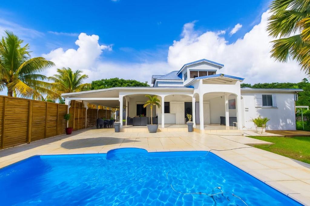 a villa with a swimming pool in front of a house at Villa Lawrencia, meublé de tourisme 4 étoiles in Morne-à-lʼEau