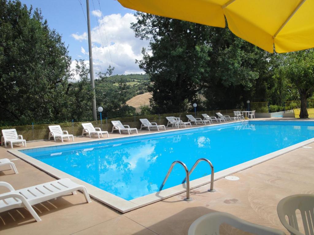 a swimming pool with chairs and an umbrella at Hotel La Meridiana in Urbino