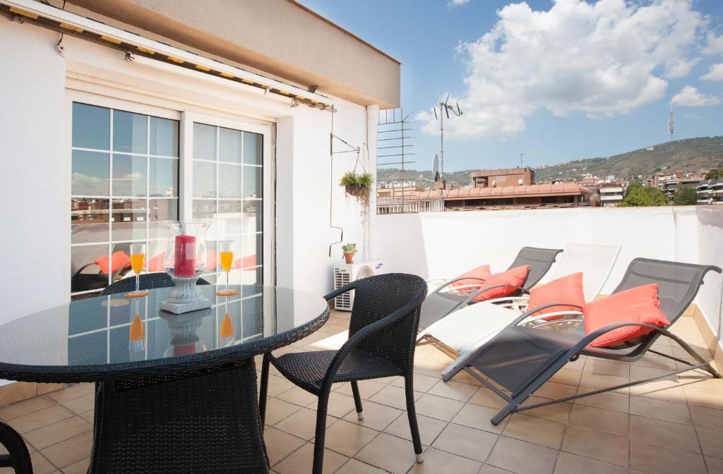 een patio met een glazen tafel en stoelen op een balkon bij Sarria Attic in Barcelona