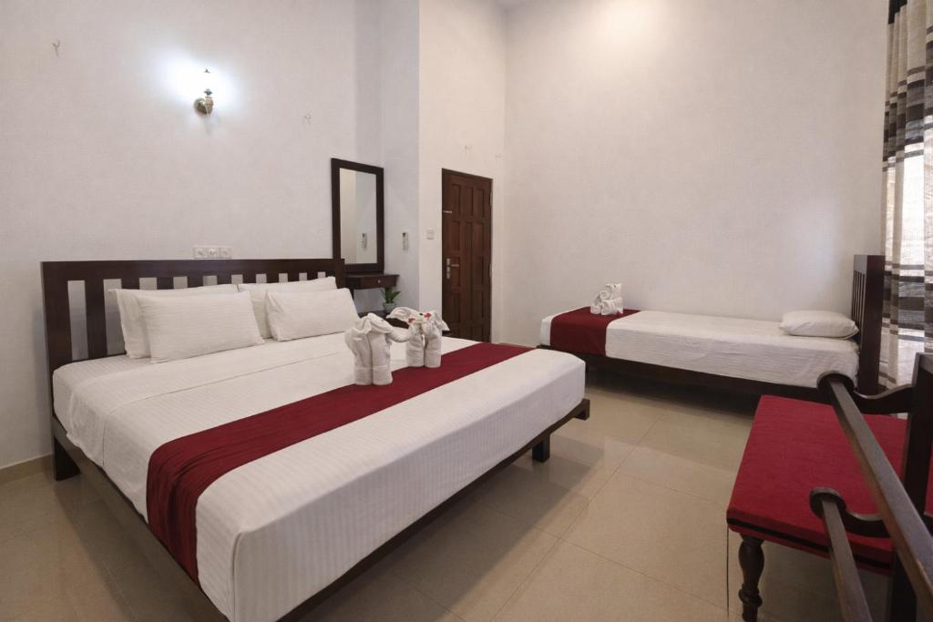 a bedroom with two beds and a table and chairs at Villa Sanitha in Ambalangoda