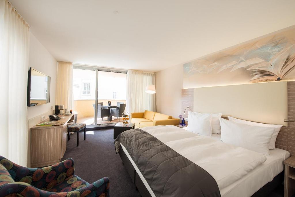 ライプツィヒにあるブック ホテル ライプチヒのベッドとリビングルームが備わるホテルルームです。