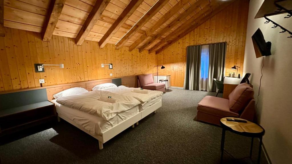 a bedroom with a bed and a couch and a chair at Hotel du Cheval Blanc in Nods