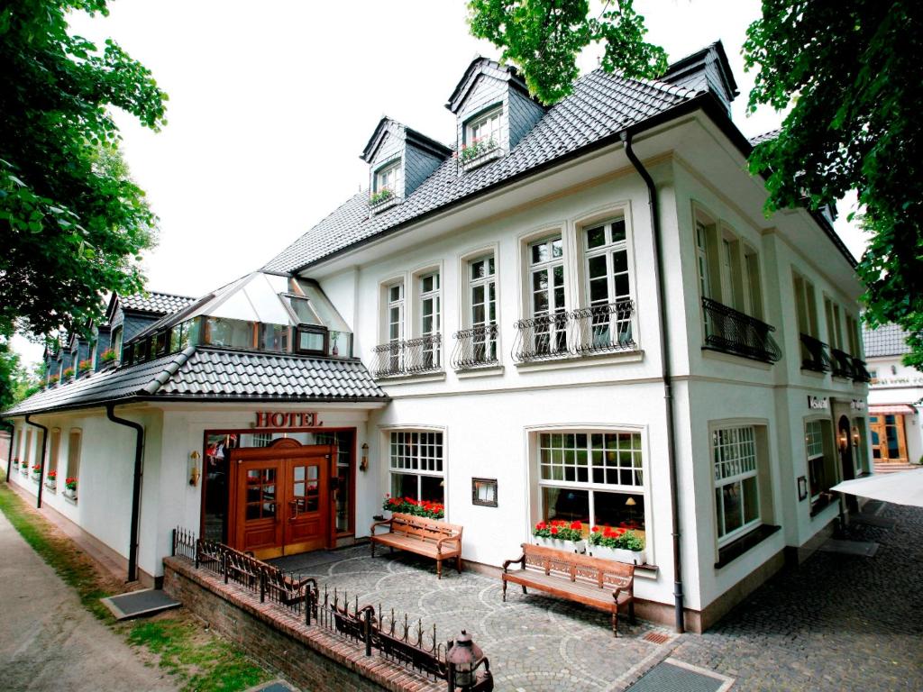 Biały budynek z ławkami przed nim w obiekcie Hotel "Schloss Friedestrom" w mieście Dormagen