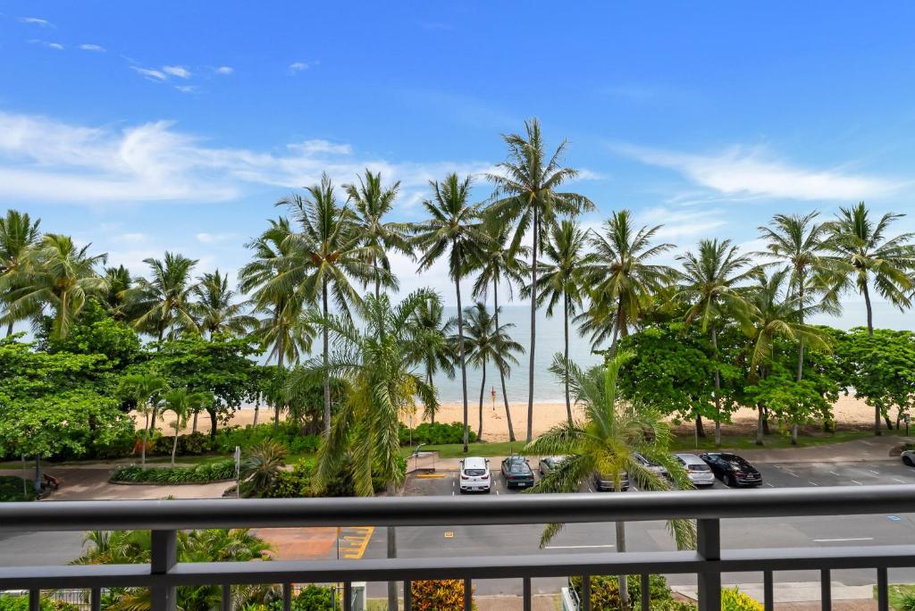 a view of the beach and palm trees from a balcony at Relax at Trinity in Trinity Beach