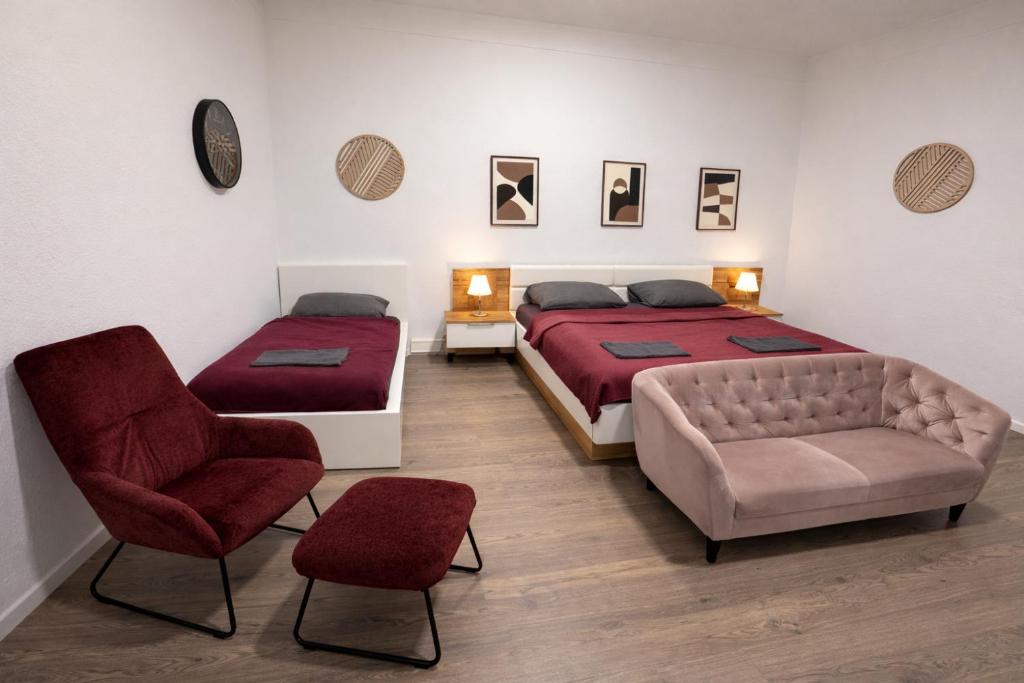a bedroom with two beds and a couch and a chair at City Rooms Koblenz Hbf in Koblenz