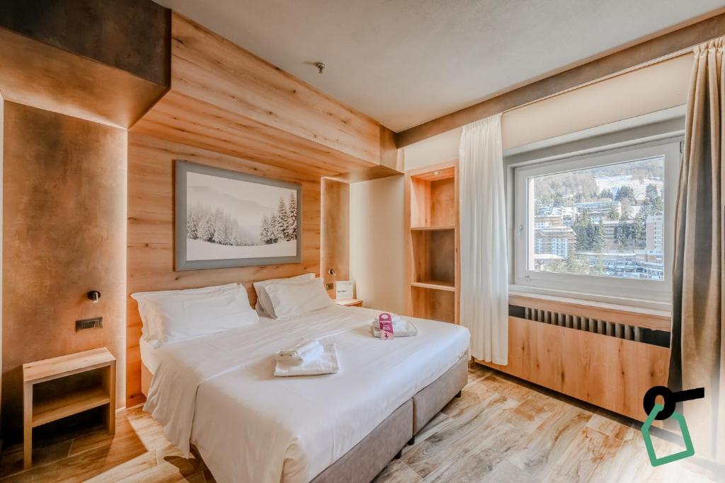 a bedroom with a bed and a large window at Hotiday Sauze Torre in Sauze dʼOulx