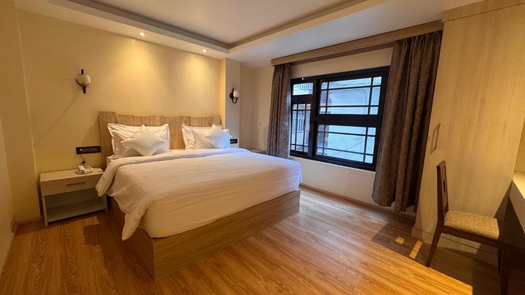 a bedroom with a large white bed and a window at Juniper Mountain Resort in Lachen