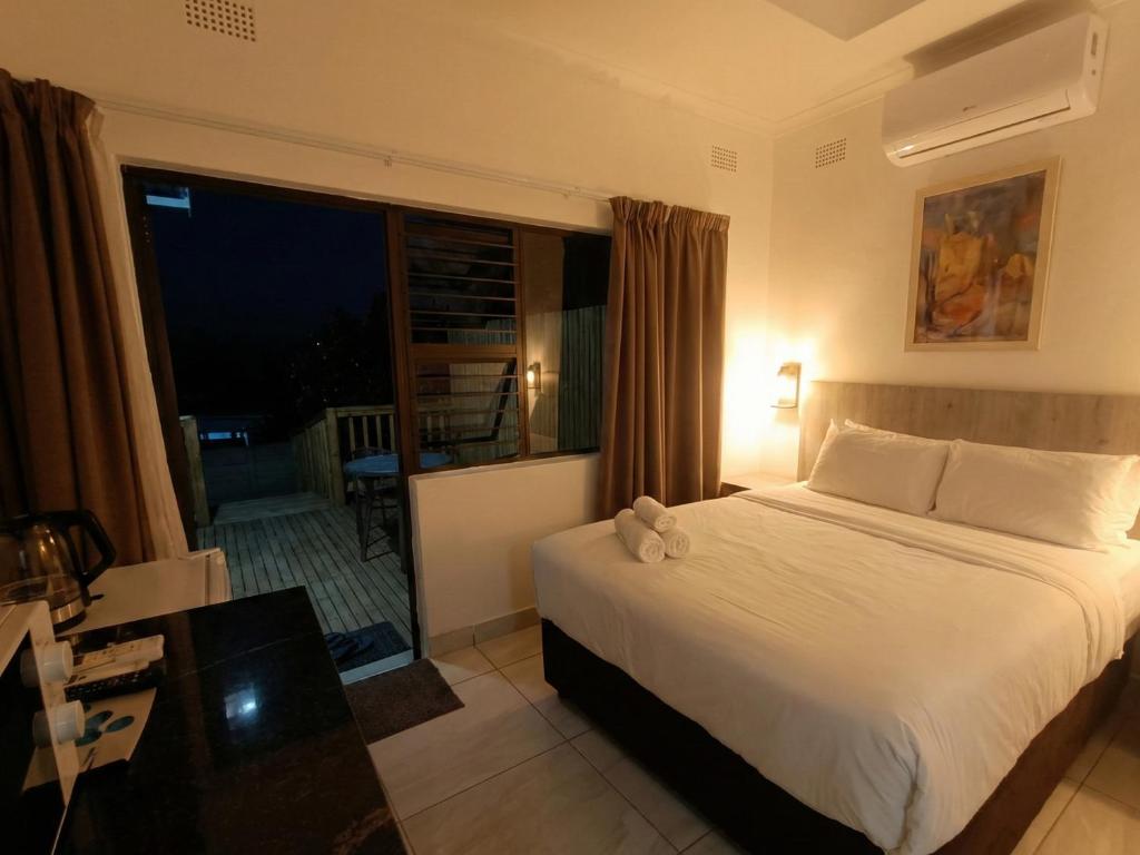 a bedroom with a bed and a large window at Rembrandt - Zur See in Ballito