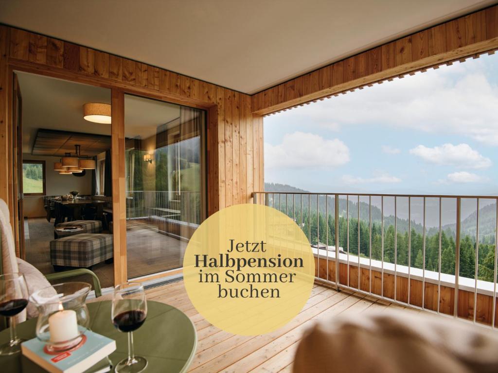 a room with a balcony with a table with wine glasses at Almresort Sonnenalpe Nassfeld in Sonnenalpe Nassfeld