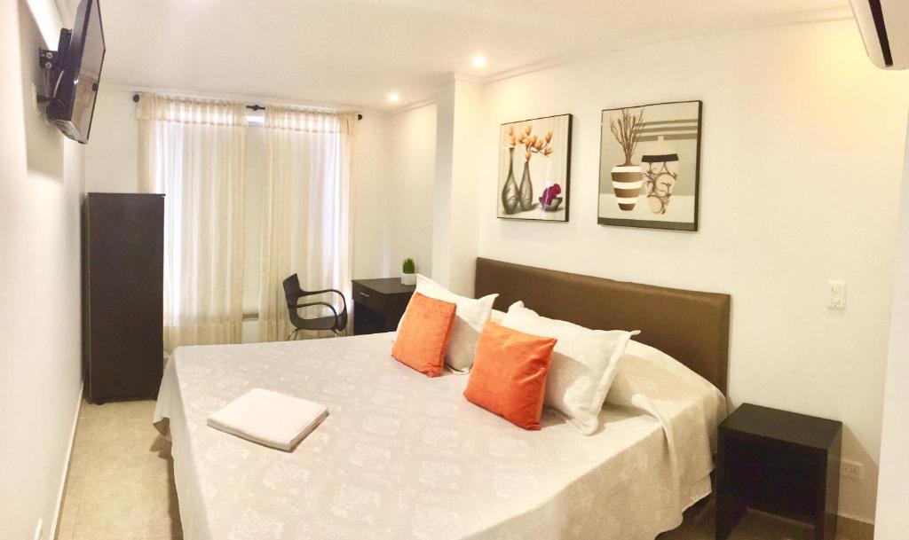 ビリャビセンシオにあるTerraza Hotel Villavicencioのベッドルーム1室(オレンジと白の枕が備わるベッド1台付)