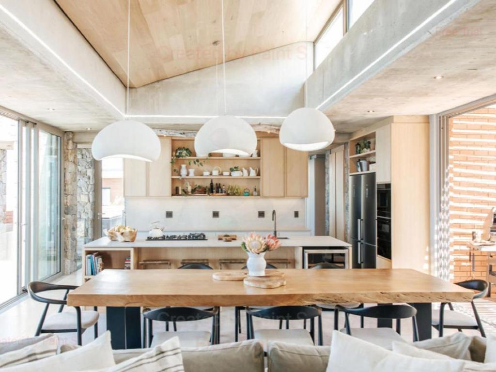 a kitchen and dining room with a wooden table and chairs at RRoar George in Herolds Bay
