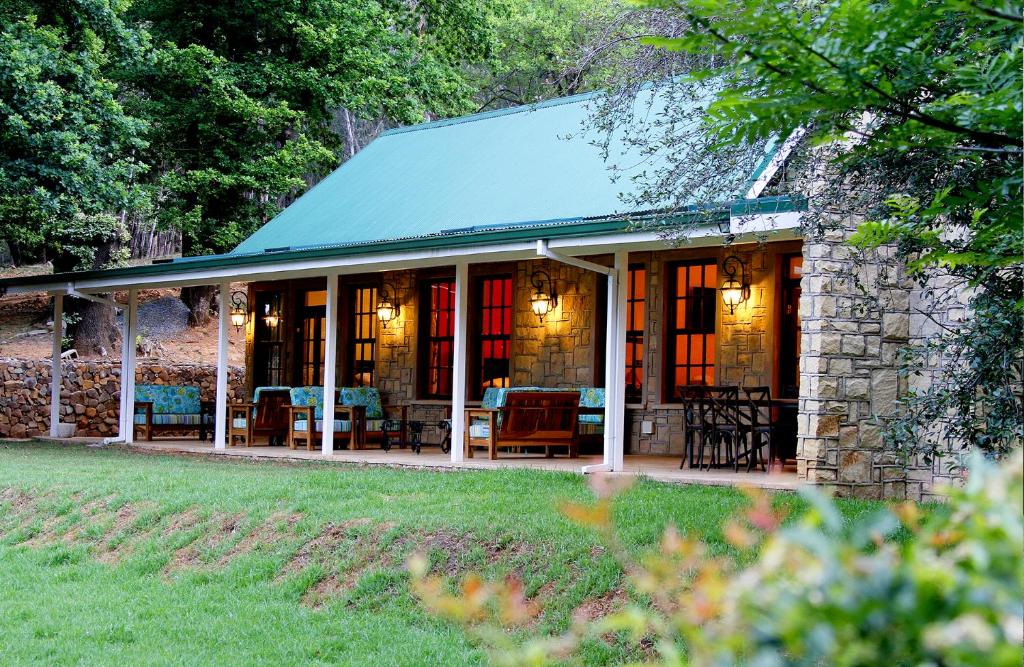 a stone house with a porch with tables and chairs at New England Cottage by First Private Stays in Underberg