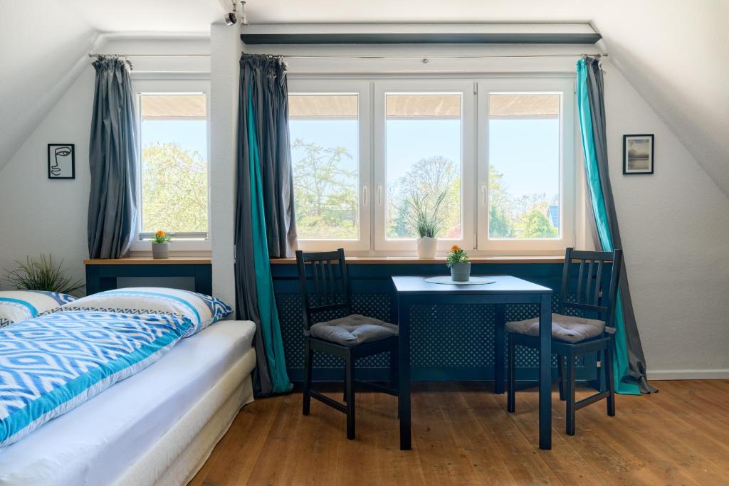 a bedroom with a bed and a table and windows at Ferienwohnung Ostseeperle Moba-Travel in Travemünde