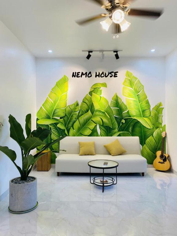 a living room with a white couch and a large mural of leaves at NEMO house in Cu Lao Thu