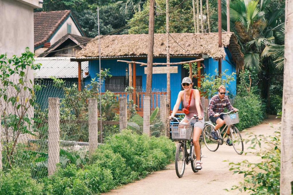 a man and woman riding bikes down a dirt road at Danh Lam Homestay in Kon Rung (1)