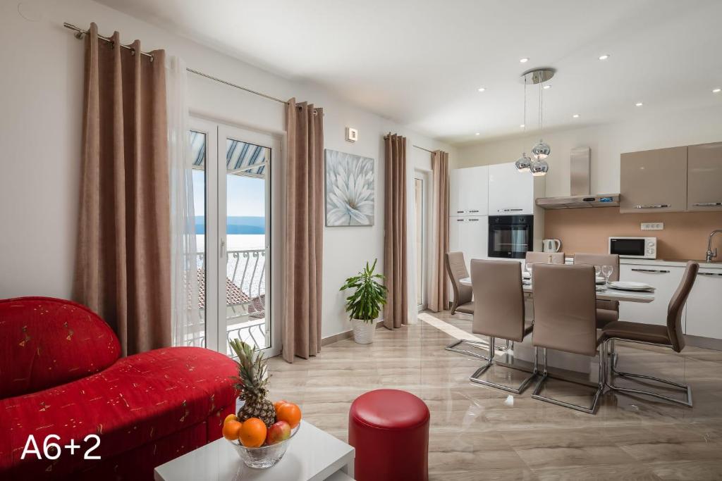 a living room with a red couch and a kitchen at Apartmani Dalibor, Stanići - Omiš in Stanići