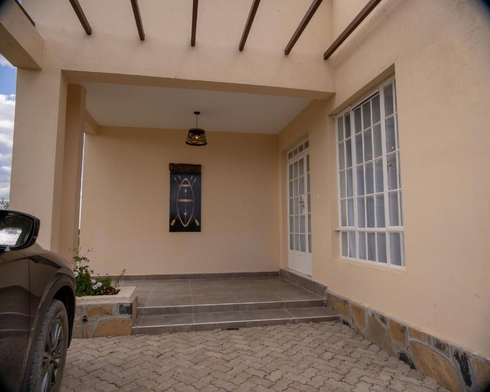 a front door of a house with a car parked outside at Ngao #220 Swara Ranch in Nanyuki