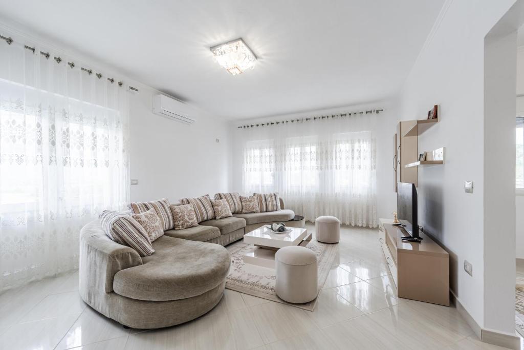 a white living room with a couch and a tv at Hometown Apartment by PikHost in Gjirokastër