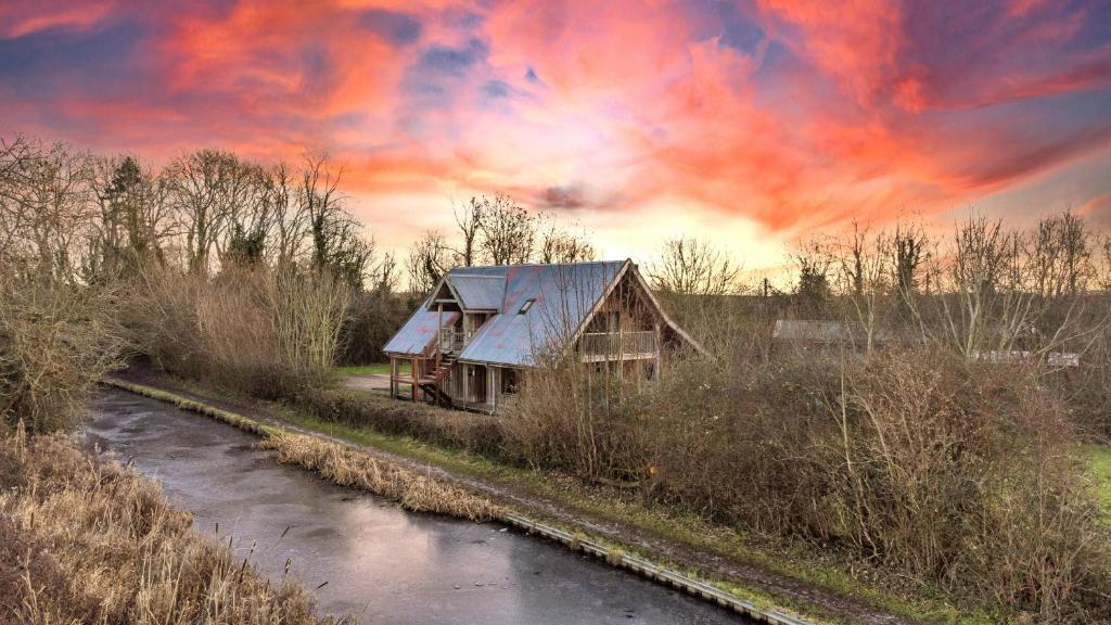 an old house next to a river under a cloudy sky at Finest Retreats - Canal Central in Ball