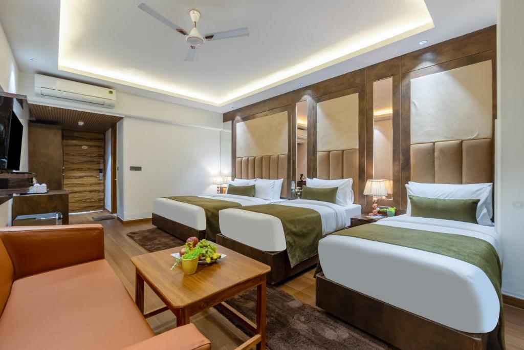a hotel room with two beds and a couch at Arch The Venus - Free Airport Pickup or Drop in New Delhi