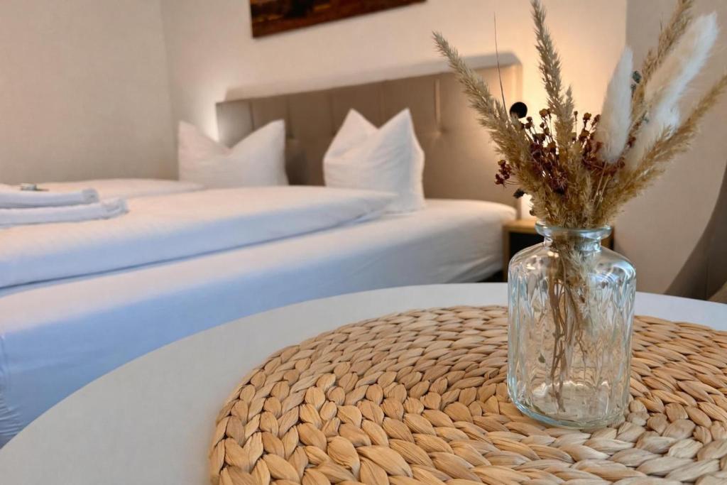 a vase with flowers on a table with two beds at DH Hotel Deutsches Haus Mittweida - Ihr digitales Hotel in Mittweida
