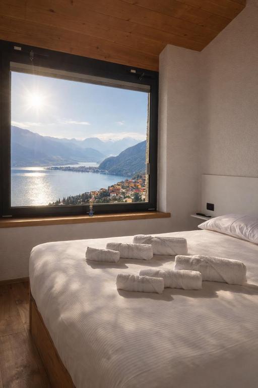 a bedroom with a large window with towels on a bed at Spigolo Nord in Bellano