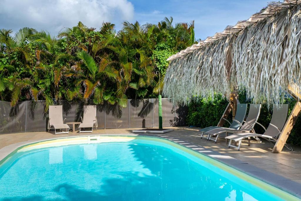 a swimming pool with chairs and palm trees at Bungalow Kaz Mendé in Sainte-Anne