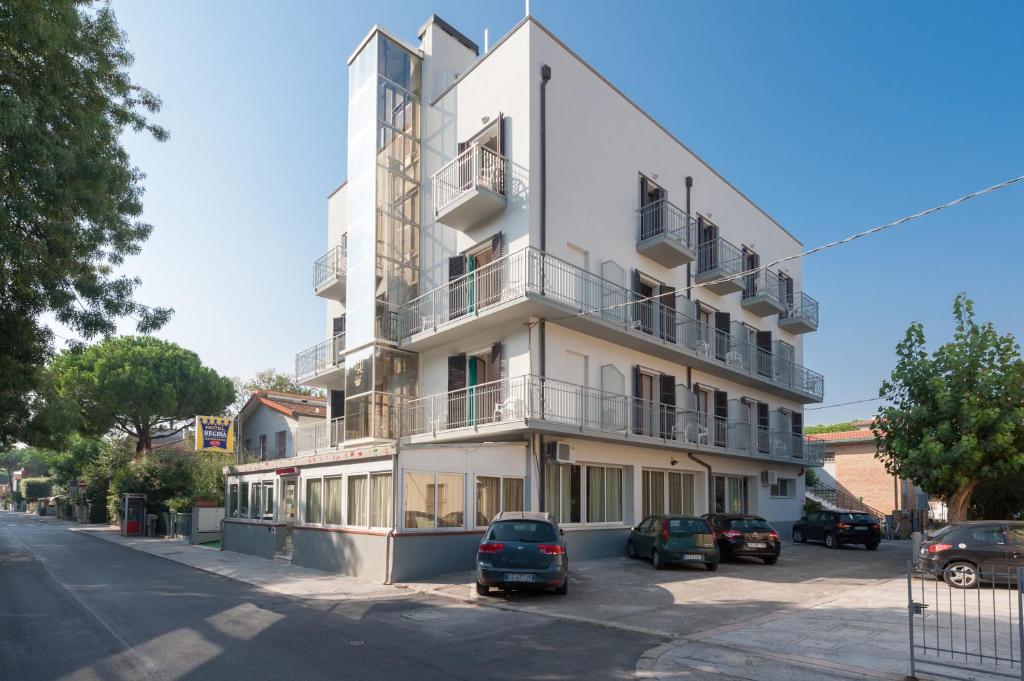 a white building with cars parked in front of it at Regina Hotel e Ristorante in Punta Marina