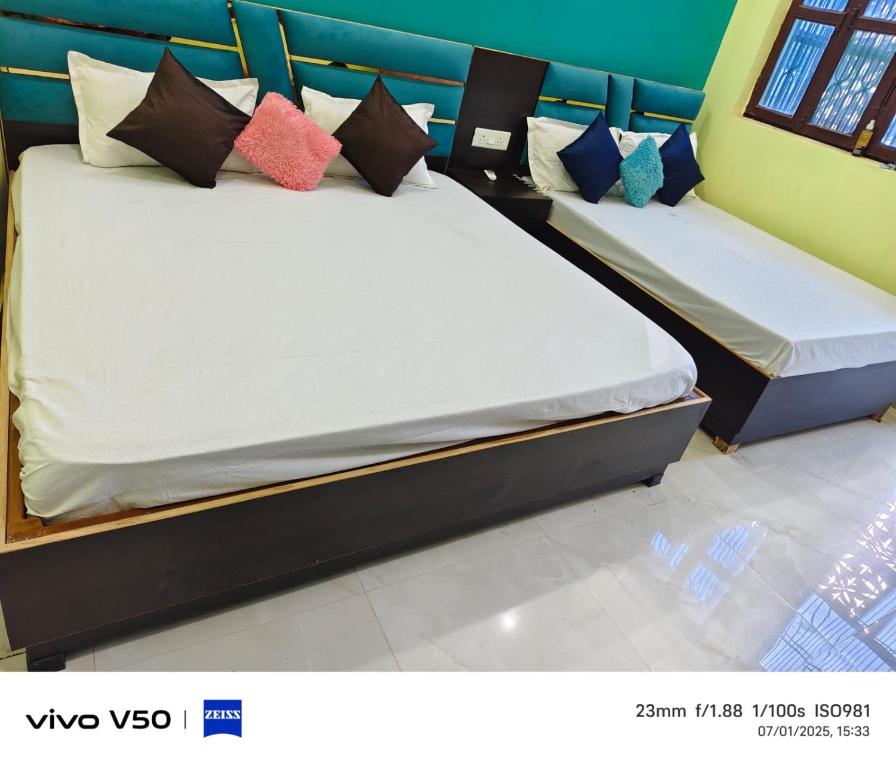two beds with colorful pillows on them in a room at Pushpanjli grand inn in Ayodhya