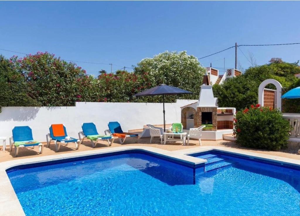 a swimming pool with chairs and an umbrella on a patio at Casa Dos Mas in Cala en Porter