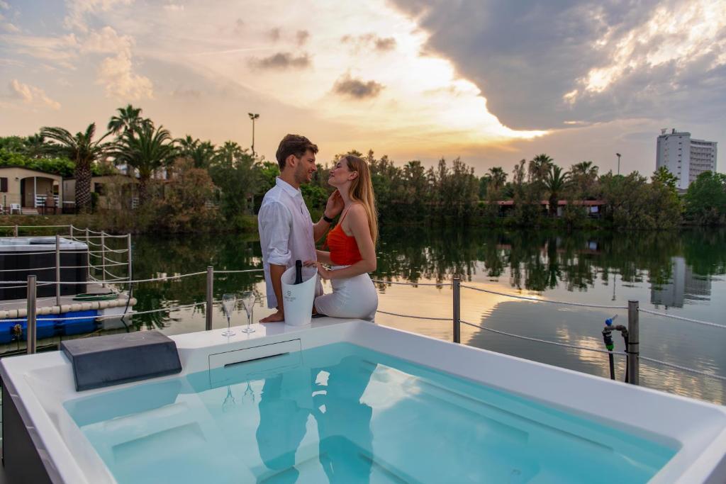 a man and woman standing on a boat near a swimming pool at Village Lake Placid in Silvi Marina