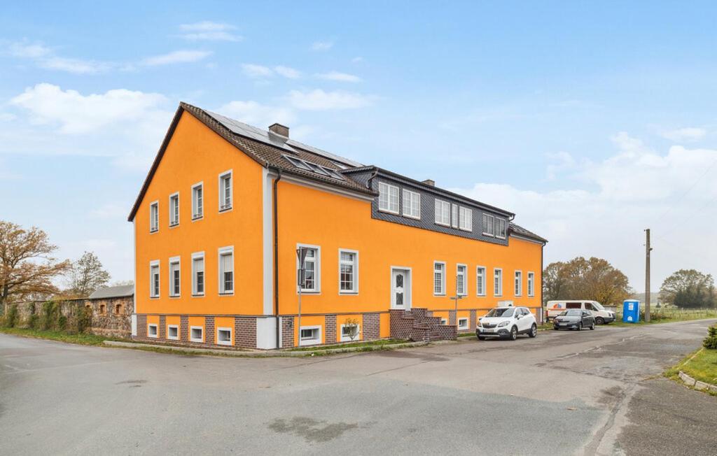 an orange building with cars parked in a parking lot at Gut Barzig in Großräschen