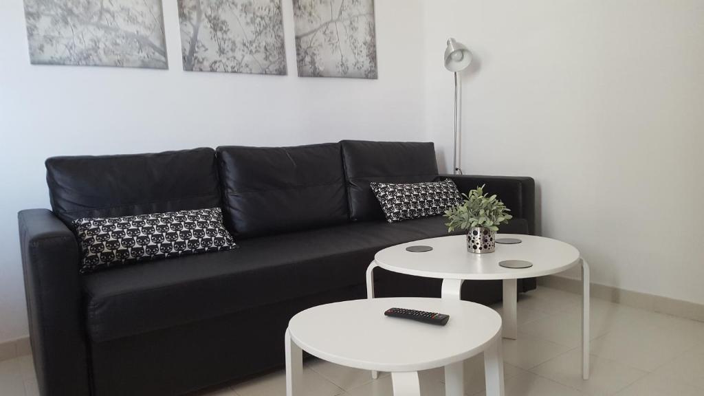 ein schwarzes Sofa mit zwei Tischen im Wohnzimmer in der Unterkunft Panelo Cactus Apartment in Puerto del Carmen