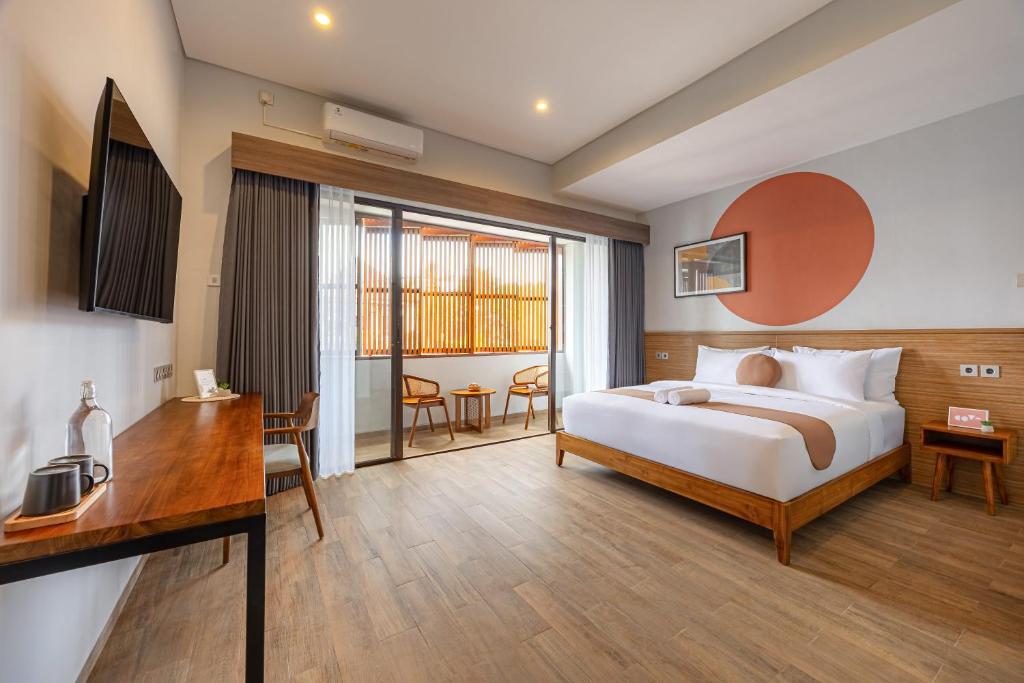 a bedroom with a bed and a desk and a room at Cove Ruma Coliving in Denpasar