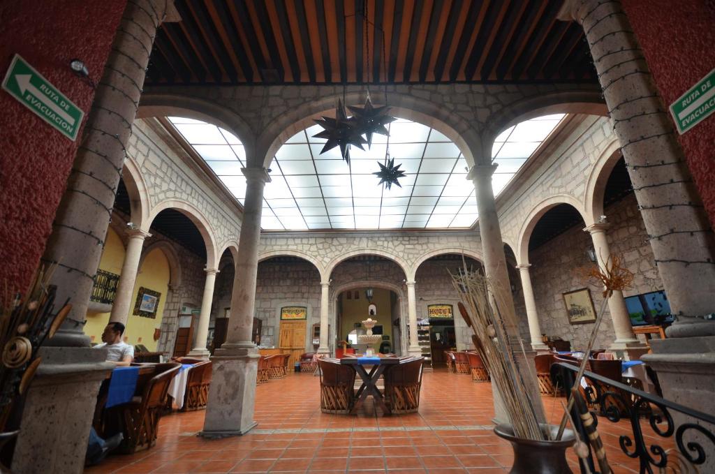 une grande chambre avec des tables et des chaises dans un bâtiment dans l'établissement Howard Johnson by Wyndham Morelia Calle Real, à Morelia