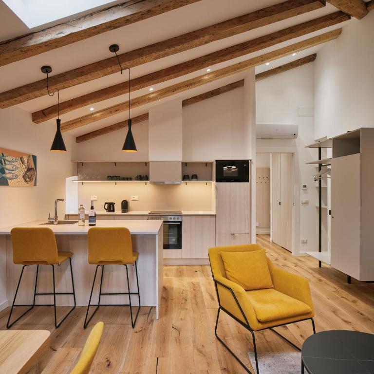 an open kitchen with yellow chairs and a counter at URBANAUTS STUDIOS Ginnastica in Trieste