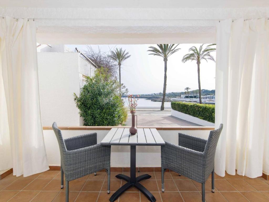a table and chairs on a balcony with palm trees at Villa Gavines down in S'Algar
