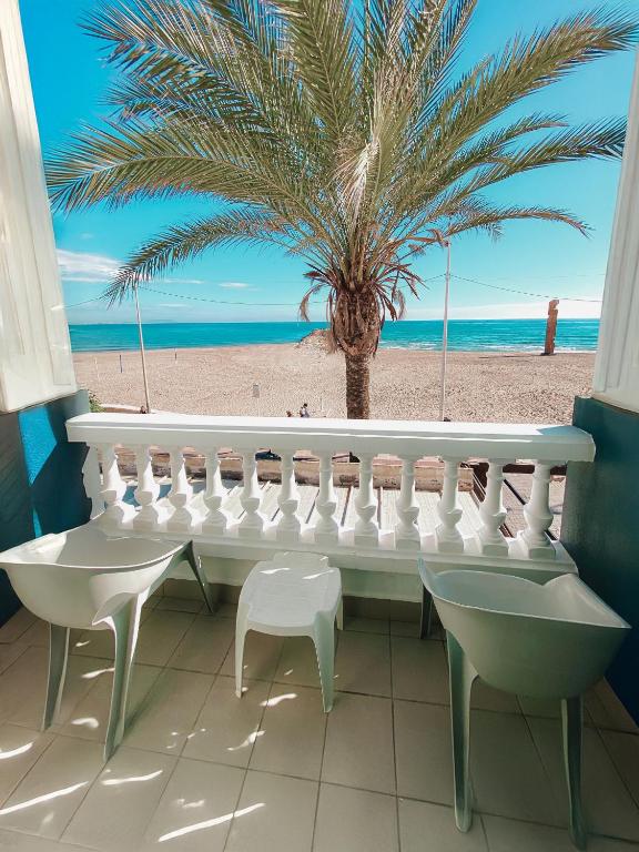 a balcony with a white bench and a palm tree on the beach at Hotel La Familia in El Campello