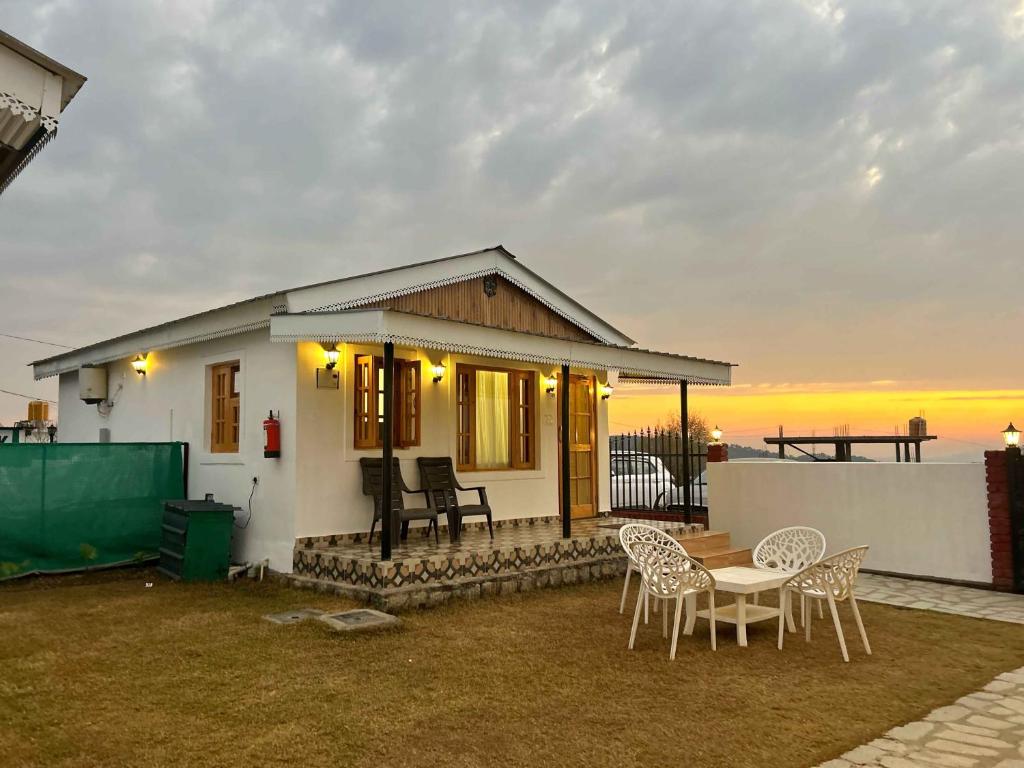 a small white house with a table and chairs at Saanjh Cottages - Hotel in Bir Billing in Bīr