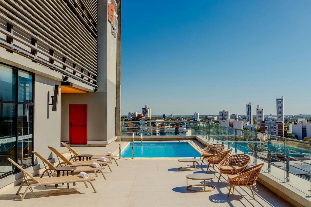a balcony with chairs and a swimming pool on a building at Aloft by Marriott Asuncion in Asunción
