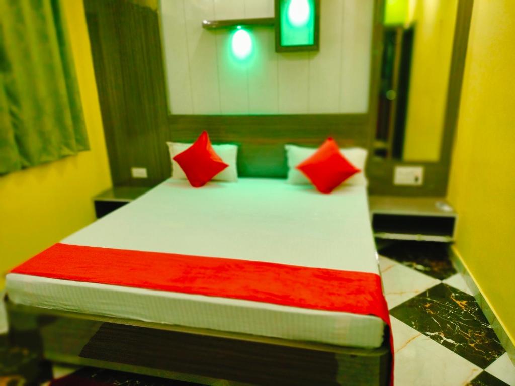 a bedroom with a bed with red pillows at Hotel Rinkesh Grand in Aurangābād