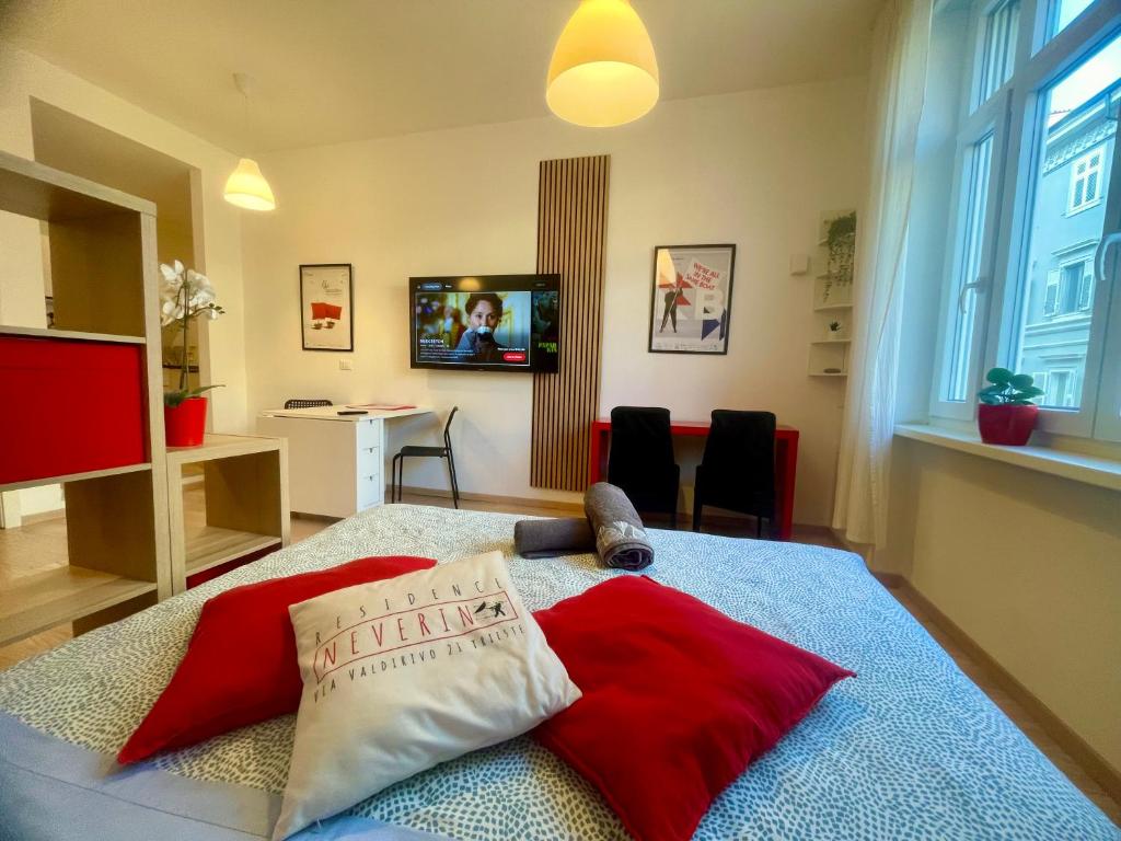 a bedroom with a bed with red pillows and a television at Residence Neverin Luxury Apartments-Private Garage in Trieste